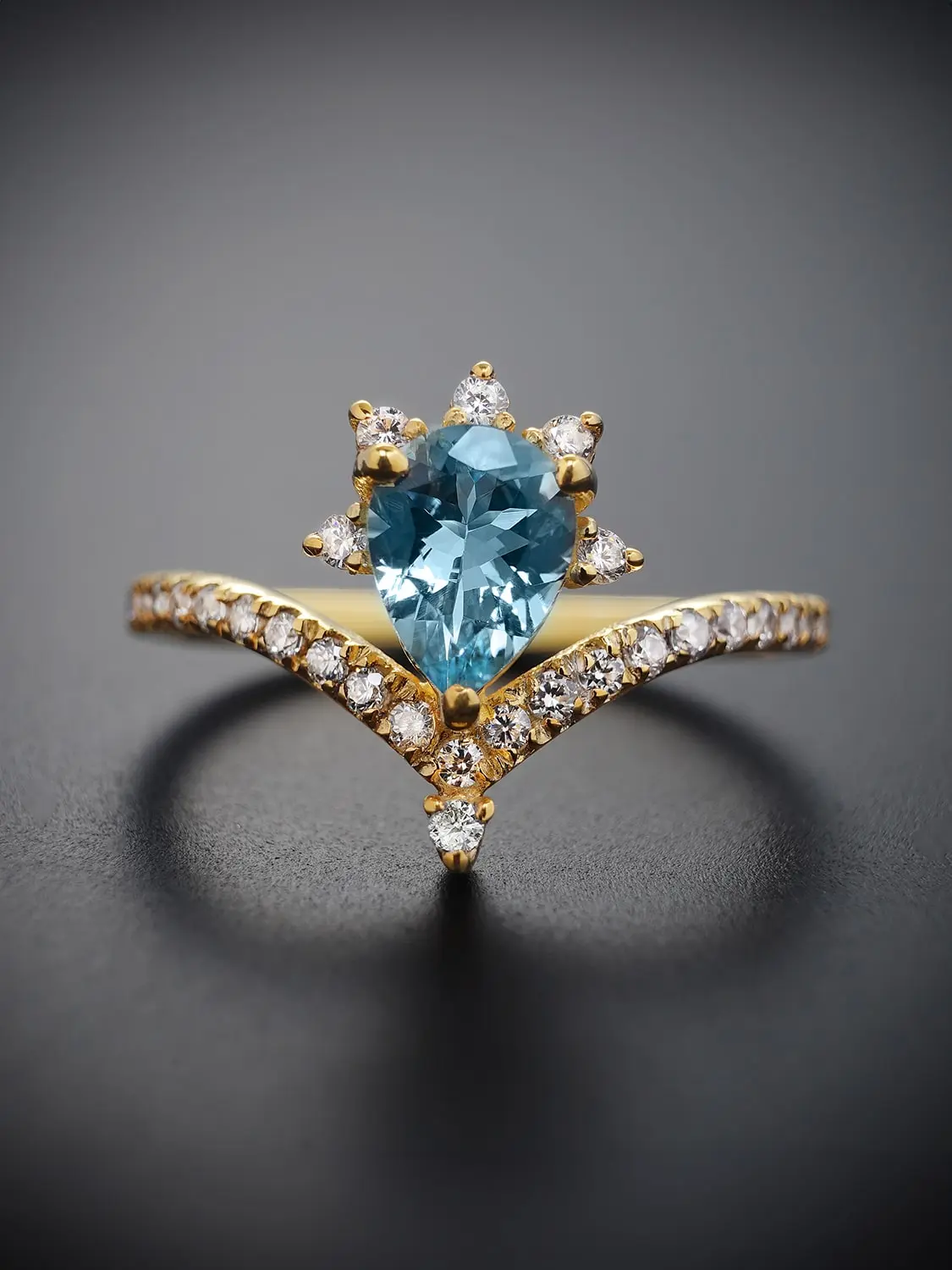 Pear-shaped blue topaz ring with moissanite accents in gold setting