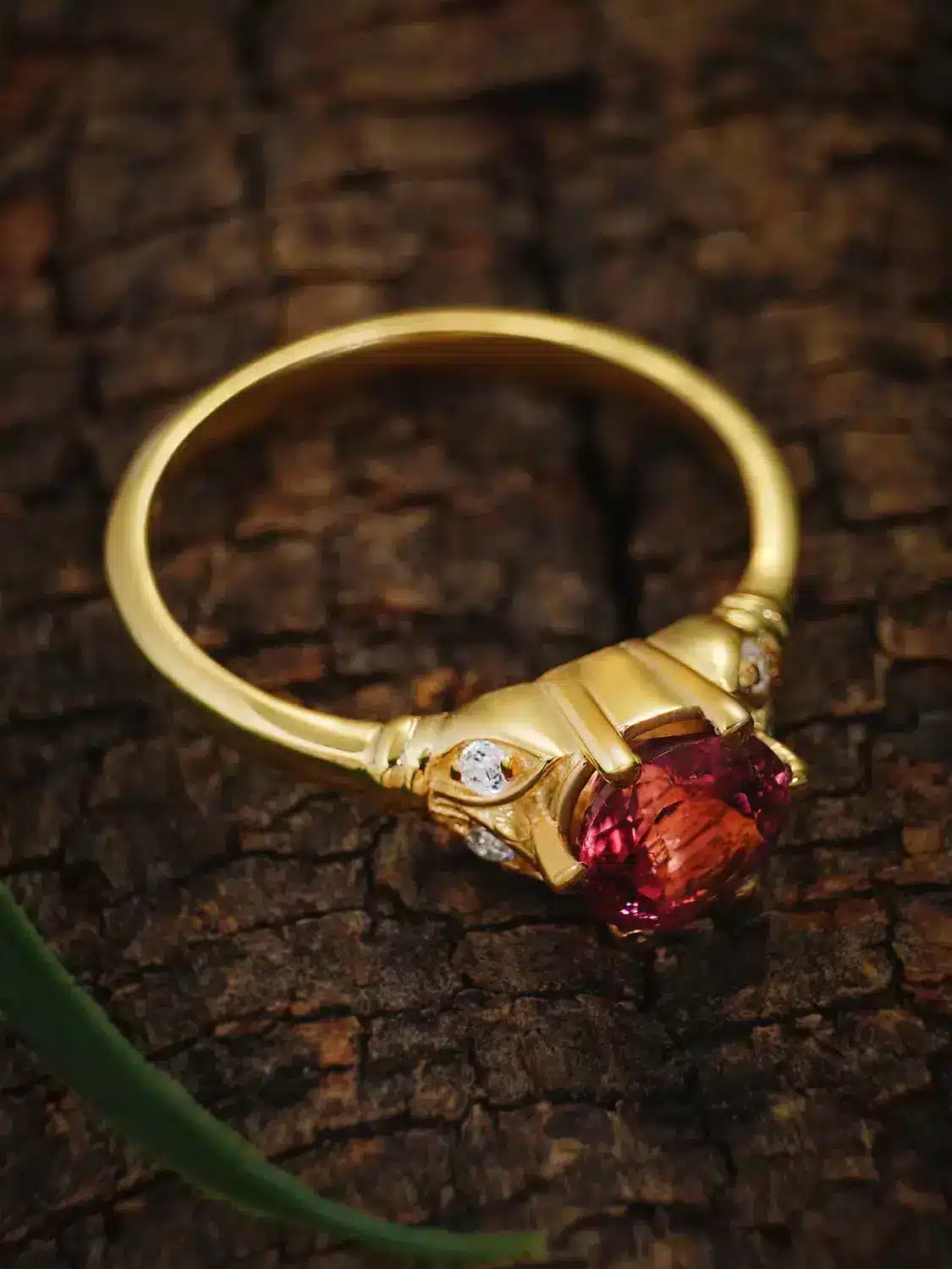 Elegant rubellite ring with moissanite accents on a wooden background