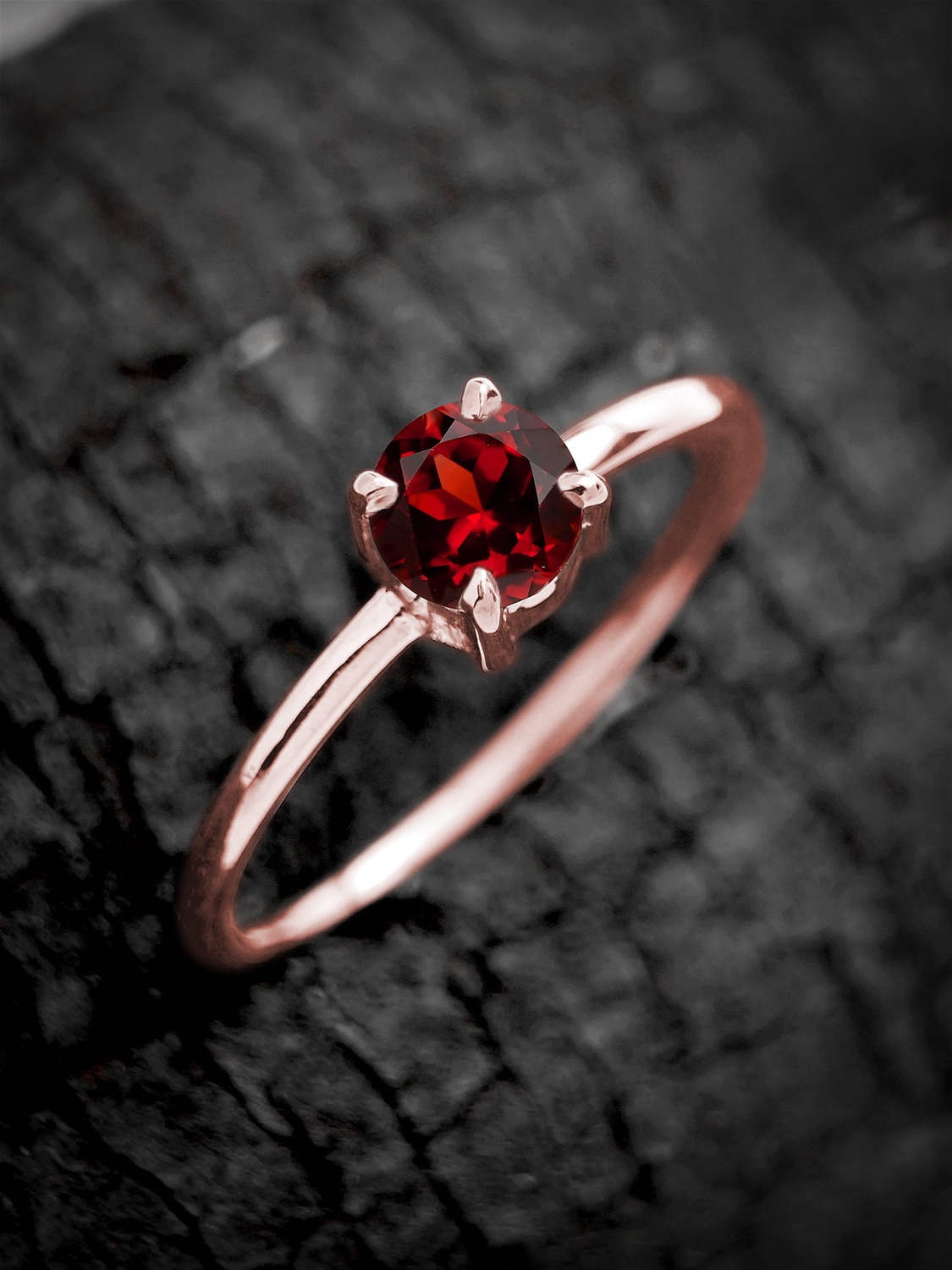 Elegant garnet ring in rose gold plating, highlighted by natural wood backdrop