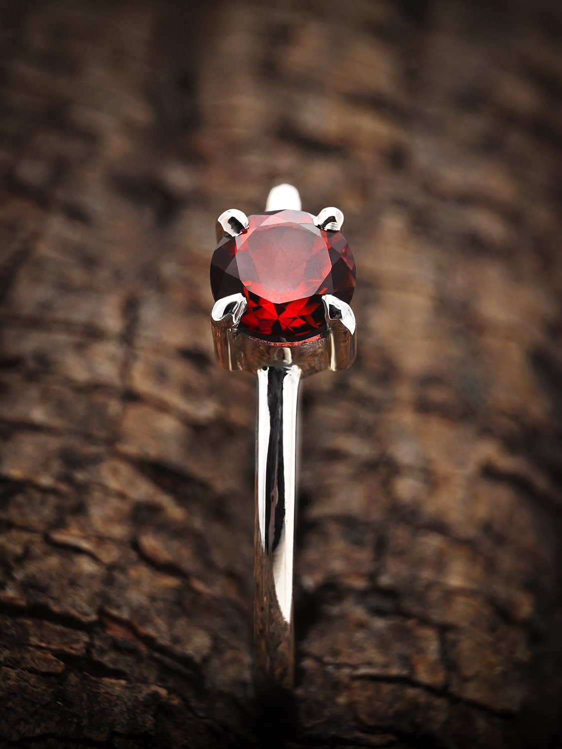 Close-up of round garnet ring in rose gold plating, emphasizing the gem's deep red hue