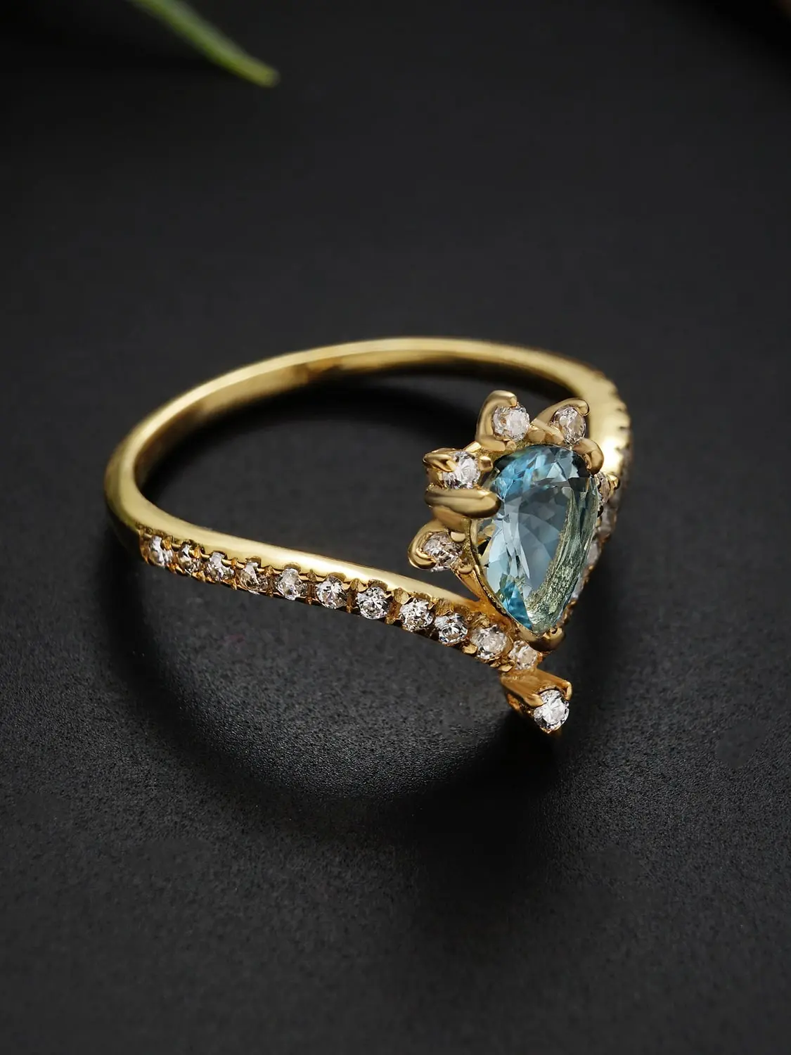 Pear-shaped blue topaz ring with moissanite accents in gold setting