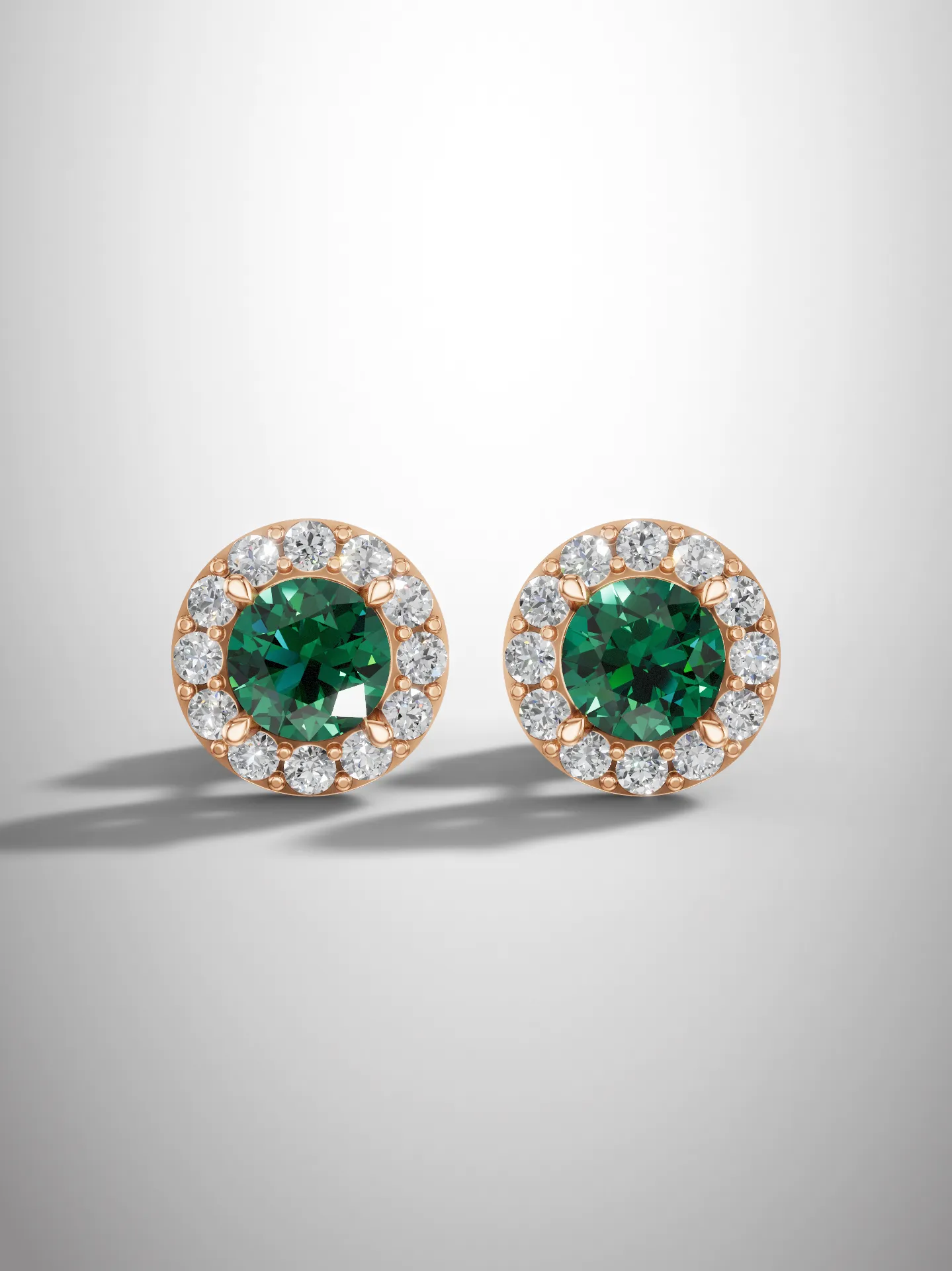 Emerald halo stud earrings Front view of emerald halo stud earrings in rose gold plating